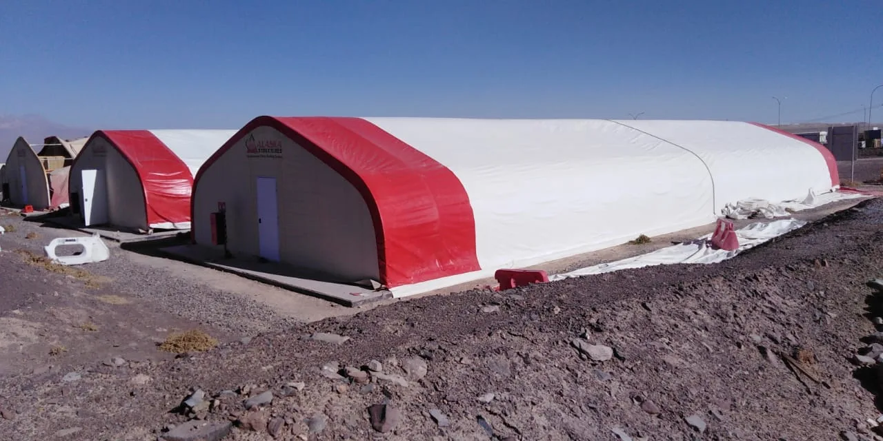 Dos galpones tipo túnel en lona roja y blanca instalados en terreno de faena
