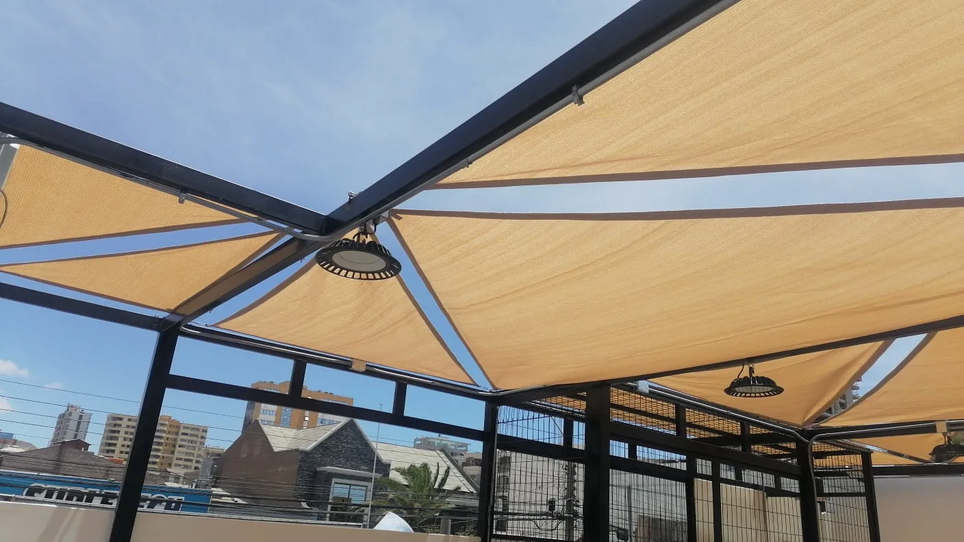 Vista interior de toldo industrial tensado con estructura metálica e iluminación